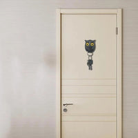 Black owl-shaped key holder on a white door