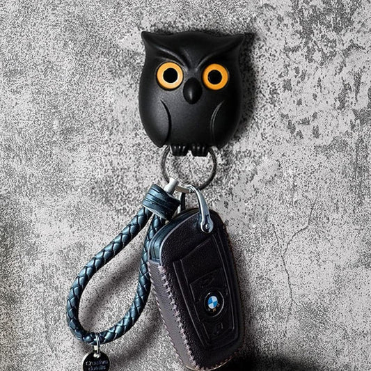 Black owl-shaped key holder with a car key on a textured gray background