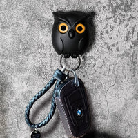 Black owl-shaped key holder with a car key on a textured gray background