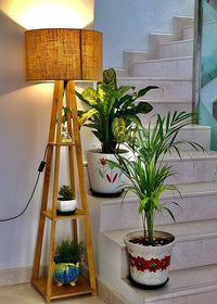 Decorative plants on a staircase with a wooden lamp and decorative pots.