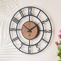 Decorative wall clock with black metal frame and wooden center on a light background