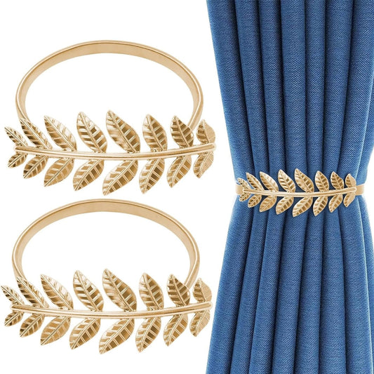 Gold leaf curtain tiebacks on a white background with blue curtains.