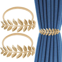 Gold leaf curtain tiebacks on a white background with blue curtains.