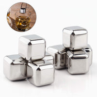 Set of silver metal ice cubes with a glass of whiskey on a wooden coaster.