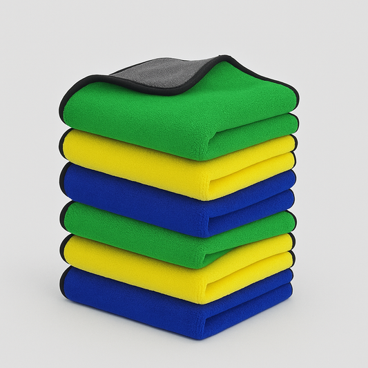 Stack of green, yellow, and blue folded cloths on a light gray background