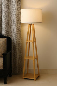 Wooden floor lamp with a white shade in a room setting.