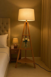 Wooden lamp with a white shade on a stand in a bedroom setting.