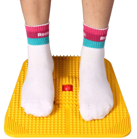 Yellow foot exercise mat with feet wearing white socks with pink and blue accents on a white background