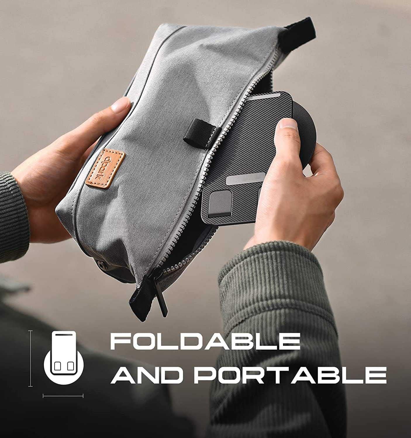 Person holding a gray foldable bag with a phone, against a neutral background